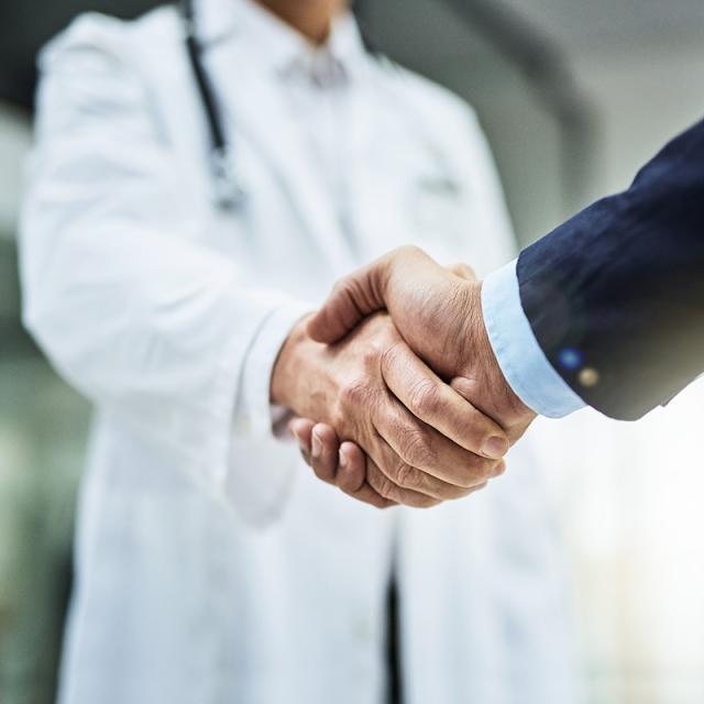 A doctor and a businessperson shake hands
