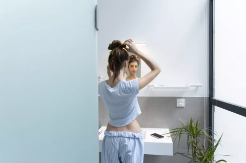 A woman looks in the mirror